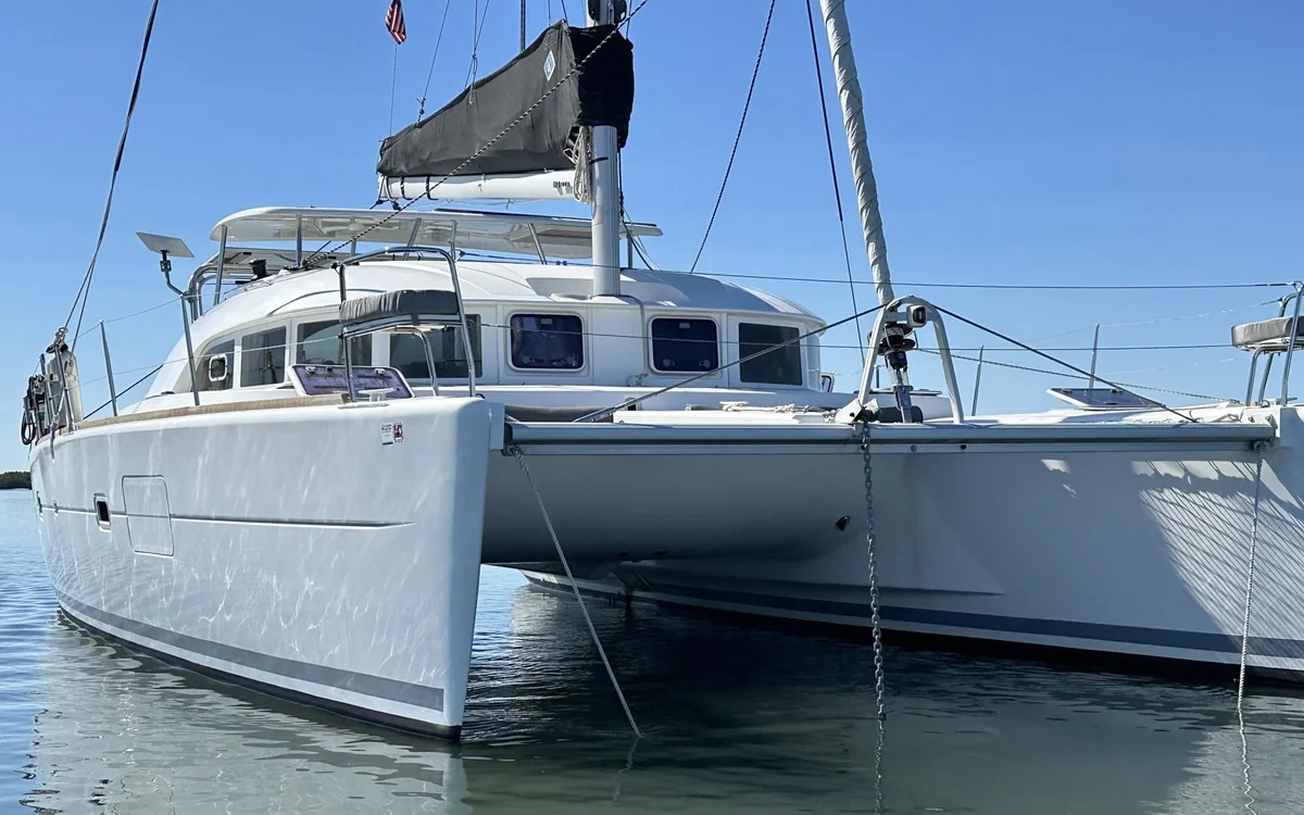 Majik bow-on at anchor on calm water, US flag in the rigging